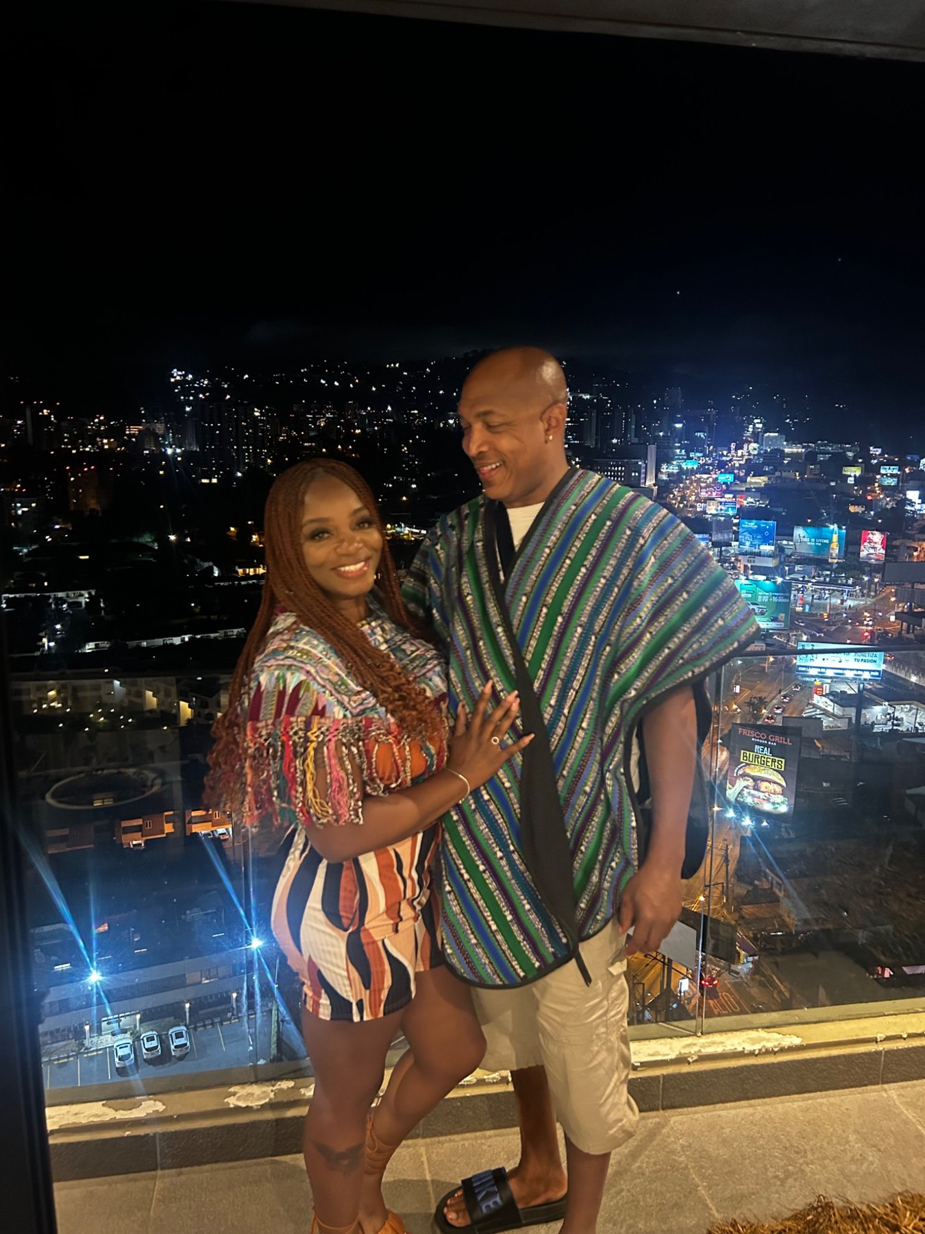 Pareja de visitantes en un balcón con vista nocturna de Ciudad de Guatemala